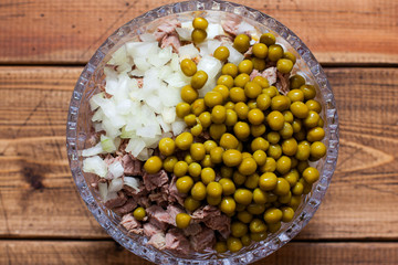 Step-by-step preparation of Olivier salad with beef, step 5 - adding chopped onions and canned green peas, top view, selective focus