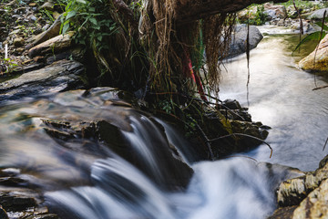 Waterfall landscape. Beautiful hidden waterfall in tropical rainforest. Jungle river. Adventure and travel to Asia. Slow shutter speed, motion photography.