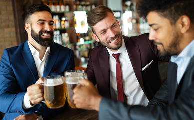 People, men, leisure, friendship and celebration concept. Happy male friends drinking beer at pub