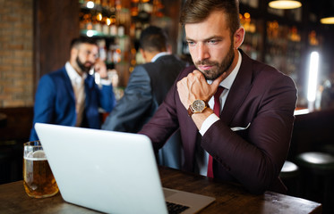 Handsome young business man, blogger or remote working with laptop in bar