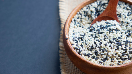 Organic natural sesame seeds wooden spoon. toasted sesame seeds. Raw, whole, unprocessed. Natural light. Selective focus. Close up on a black background. Top view, flat lay. copy space for text.