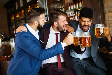 People, friendship and celebration concept. Happy business male friends drinking beer at pub