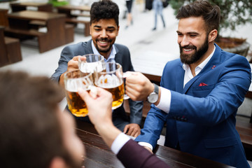 People, men, leisure, friendship and celebration concept. Happy male friends drinking beer at pub