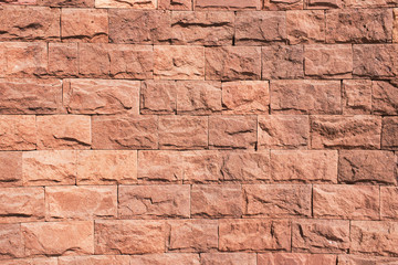 Red brick wall. Horizontal decorative uneven blocks background. Urban architecture texture. Solid stone texture. Grunge brickwork structure.