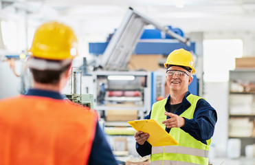 Engineer and a manager working together in a factory, wearing protective wear