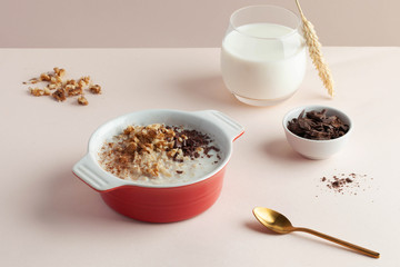 Oatmeal porridge with nuts, chocolate on a soft pink background. Food styling, trends in food photography. Good morning.