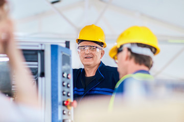 An engineer and a manager working together in a factory, wearing protective wear