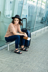 Fototapeta premium Sad Woman sitting outdoors at airport and waiting for her flight