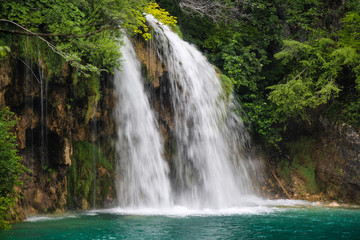 Naklejka na ściany i meble A waterfall flowing into a lake at Plitvice Lakes, Unesco world heritage site