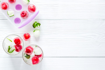 Raspberry and lime in ice cubes on white table top view copy space