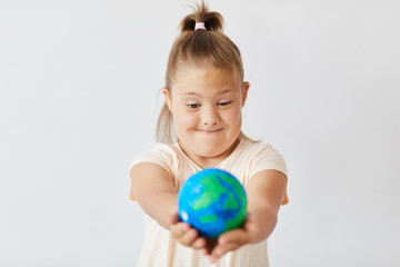 Girl with down syndrome looking at the Earth planet in her hands isolated on white background