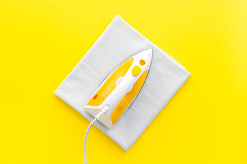 Yellow iron with clean linen on ironing board. Top view, copy space