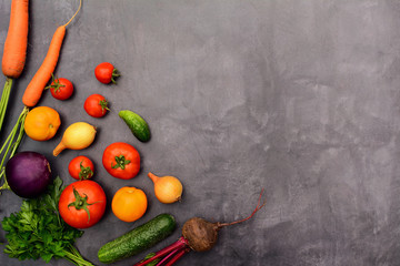 Tomatoes, cucumbers, eggplants, onions, carrots and beets, parsley - layout on a gray background with side space for design. Seasonal vegetables