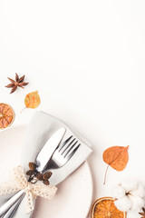 Thanksgiving autumn background. Plate with Cutlery and napkin decorated with autumn leaves, berries and spices. Top view.