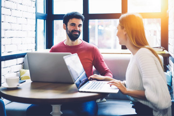 Young skilled male and female copywriters working together in friendly atmosphere collaborating to...
