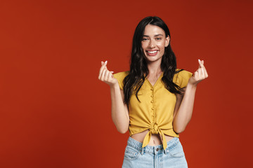 Image of young excited woman rubbing her fingers together and smiling