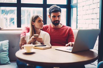 Couple in love spending free time together in cozy coffee shop watching favorite movie online on laptop, lovers searching items in web store browsing webpage on modern netbook enjoying leisure