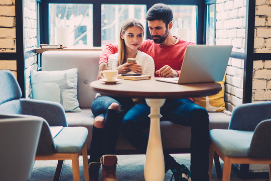 Romantic couple in love viewing photos of friends from social networks via modern laptop resting in cafe, lovers spending time together enjoying watching movie online in comfortable coffee shop