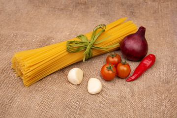 Raw Pasta with ingredients on linen or jute sacking or fabric