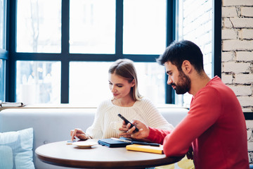 Millennial couple in love ignoring live communication during leisure time for blogging prefer...