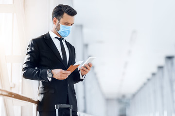 Entrepreneur in face mask using phone while waiting for flight