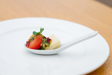 A small piece of tomato. Banquet service. catering food, snacks with cheese, jamon, prosciutto and fruit. Snacks for buffet at the reception. Decorated catering banquet menu.