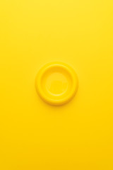 Minimalist photo of yellow pet bowl on the yellow background. Vertical orientation overhead image of empty cat bowl.
