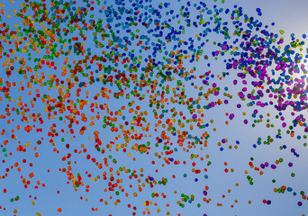A thousand colorful balloons are flying in the blue summer sky. Texture.