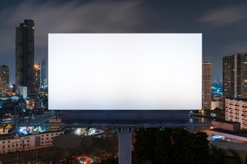 Blank white road billboard with Bangkok cityscape background at night time. Street advertising poster, mock up, 3D rendering. Front view. The concept of marketing communication to promote idea.