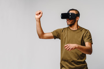 Young African American man wearing vr virtual reality headset over grey background