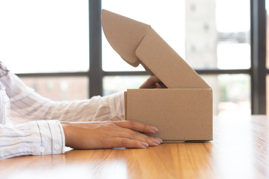 Woman opening box with new parcel, close-up