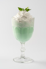 Mint milk protein shake, with whipped cream and mint syrup on a white plate.