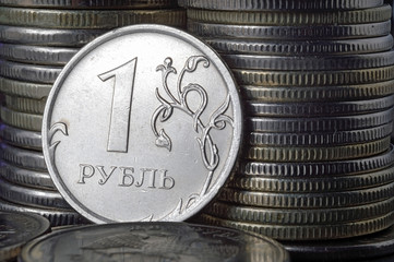 Russian 1 ruble coin (reverse) against the background of other coins folded in columns.