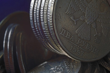 Russian coin in denomination of 10 rubles (reverse) against the background of other coins folded in columns.