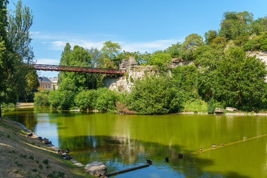 Lake in the Parc Buttes-Chaumont with footbridge in the background - Paris, France