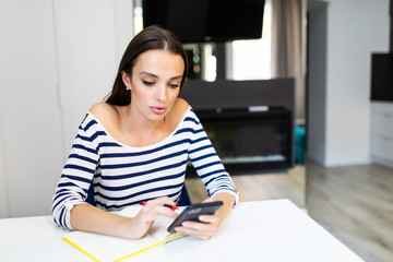 Young woman at home planning family budget and finances or calculated bills in the kitchen