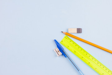 Essential school stationery on a light blue background. View from above. Place for text.