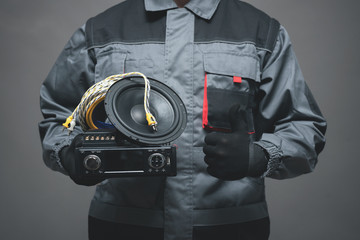 Car audio specialist is holding in hand a car stereo equipment and is showing a thumbs up. - obrazy, fototapety, plakaty