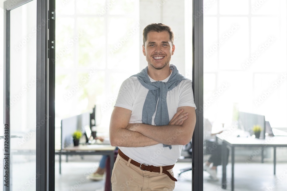 Canvas Prints Happy businessman standing in the office with coworkers in the background working by the desk