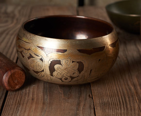 Tibetan singing copper bowl with a wooden clapper on a brown wooden table