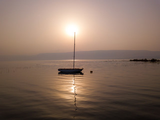 Sunrise over the lake. Boat floating on the calm water under amazing sunset.