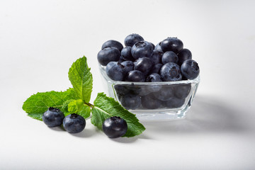 Blueberries on a white background in a glass Cup. Blueberries in a Cup and a sprig of fresh mint.