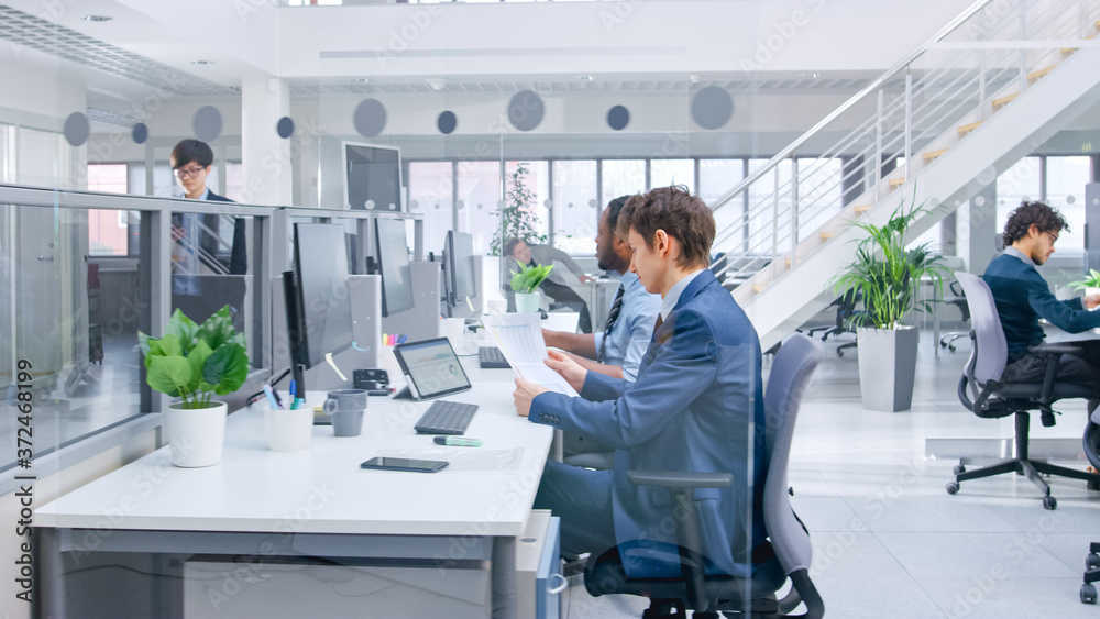 Aufkleber in modern office: diverse team of managers and specialists work on computer, have discussion with co