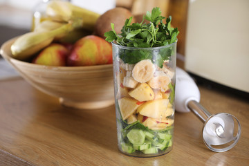 Glass of delicious yogurt with mint and fresh strawberries, banana, lime, nectarine in a wicker basket on a wooden table