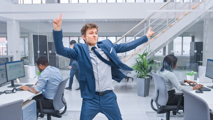 Young Cheerful Handsome Business Manager Wearing a Suit and Tie Dancing in the Office. Diverse and...