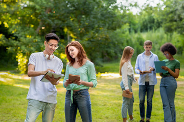 Fototapeta premium Group of multi ethnic college friends spending time together outdoors, having break