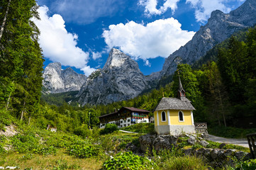 Fantastic view of a chapel and an alpine hut in the Kaiser valley surrounded by forest and the rough Kaiser Mountains.