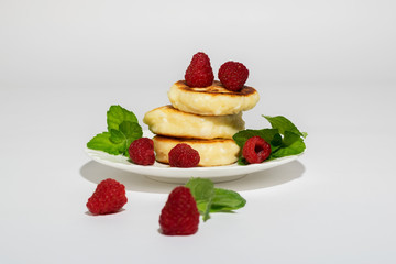 Delicious and healthy cottage cheese pancakes on a white saucer, poured with BlackBerry jam.