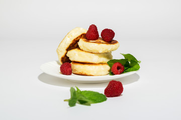 Delicious and healthy cottage cheese pancakes on a white saucer, poured with BlackBerry jam.