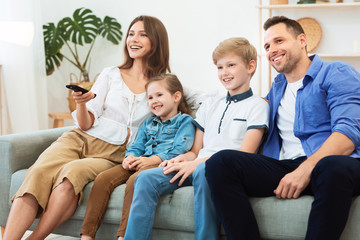 Family Of Four Watching TV Relaxing On Weekend At Home